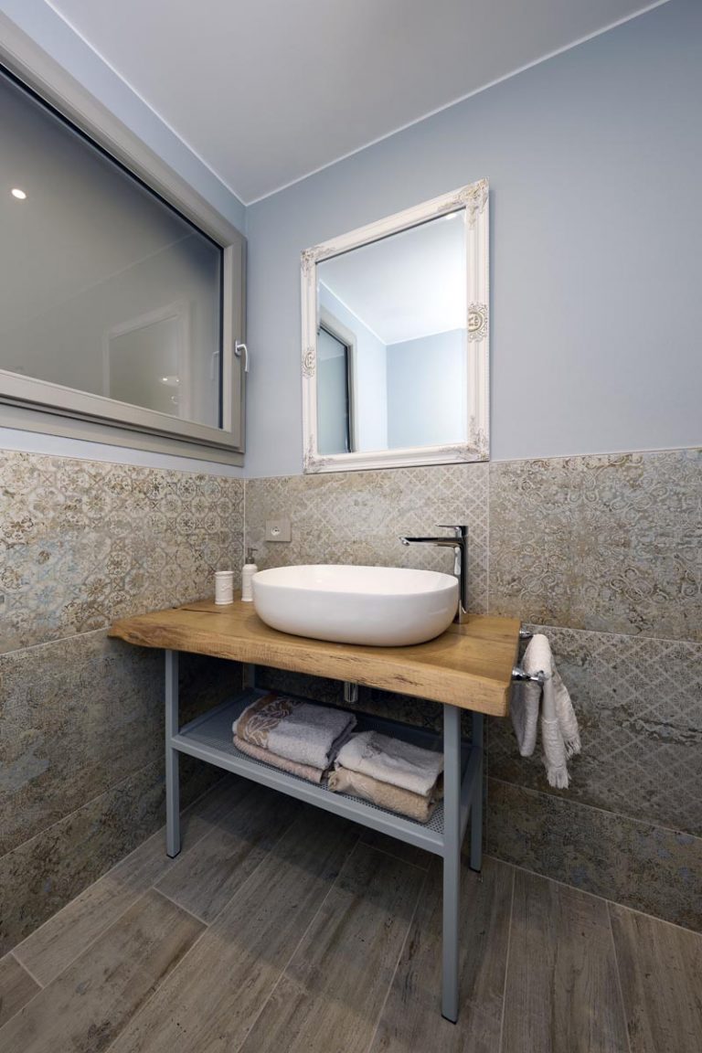 bagno con pavimento effetto legno e rivestimento gres anticato presso residence lago di Garda