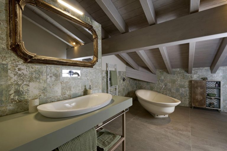 bagno con travi a vista, pavimento gres e rivestimento residence lago di Garda